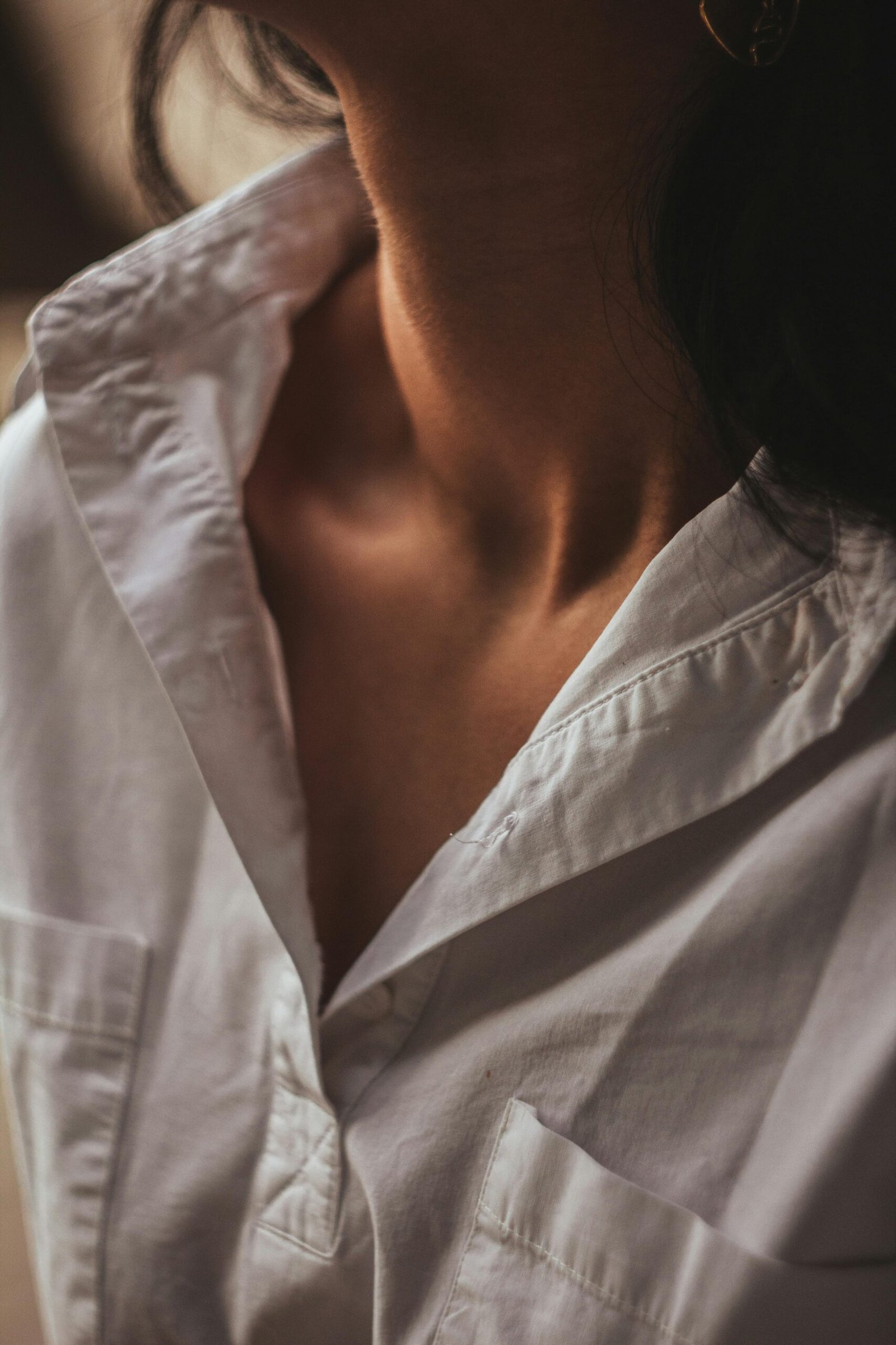 Intimate close-up of a woman wearing a white blouse, highlighting texture and detail.